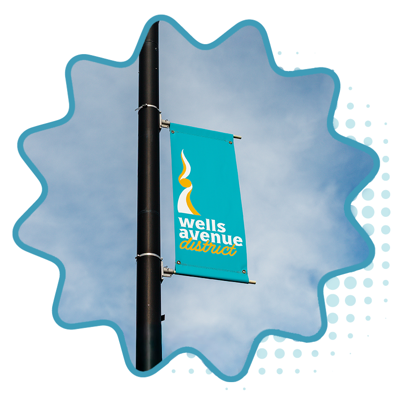 A banner attached to a light pole that has the logo mark for Wells Avenue District.