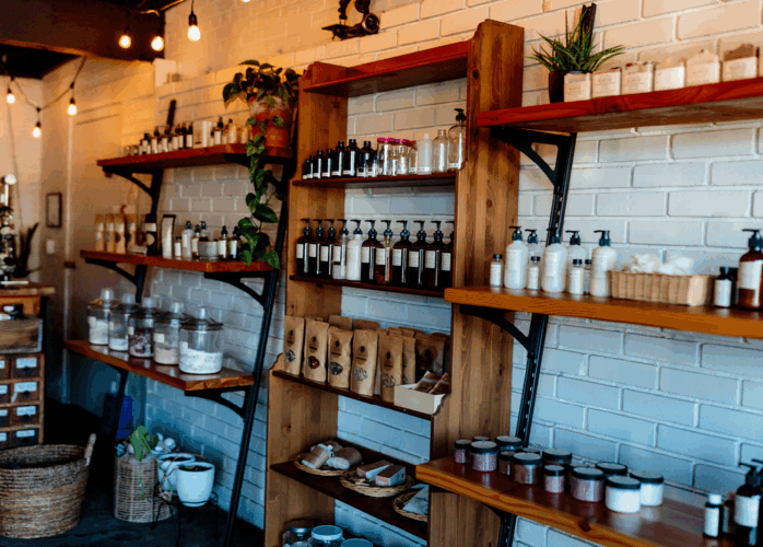Three shelves of natural products against a white brick wall.