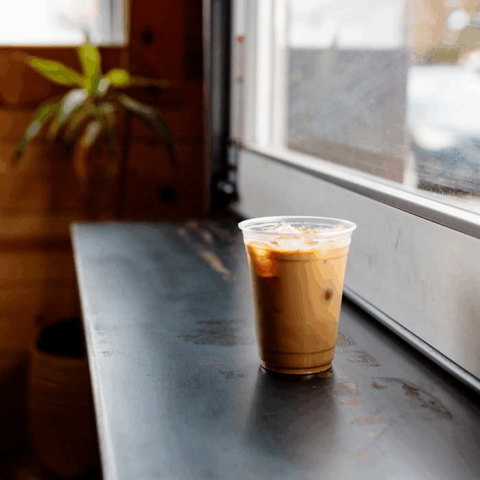 An iced coffee sits on a black bar.
