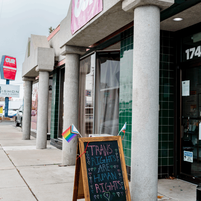 The outside of Our Center. In front of the door is a black chalkboard sign that reads, "Trans Rights are Human Rights."